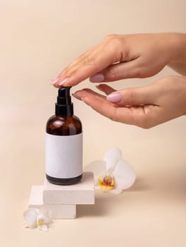 A woman hand pumping liquid on a cupped hand from a cosmetic bottle near orchid flowers on beige close up, label mockup. Skincare beauty product package, minimal composition..