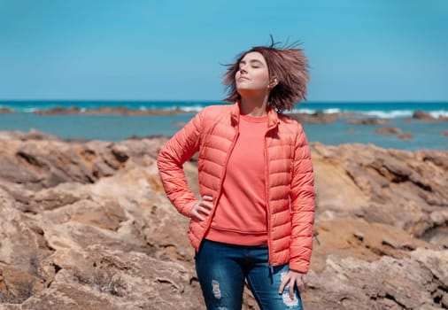 Happy Teen girl wearing pink shirt and pudded jucket, mockup. Teenager standing outdoor near the sea in a sunny day, spending her time alone. Adolescence concept