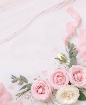 Pink and cream roses and silk ribbons on white marble top view. Romantic flat lay with pastel flowers. Wedding, Valentines, Spring or Mothers day concept