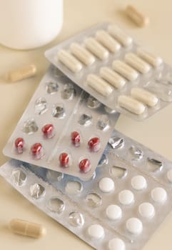 Mix of pills and capsules in a aluminum and plastic blisters with some missing pills already used on light beige close up. Preventive medicine and healthcare, taking dietary supplements and vitamins
