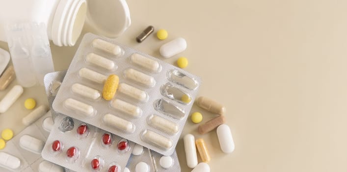 Mix of pills and capsules in a aluminum and plastic blisters with some missing pills already used on light beige close up, copy space. Preventive medicine and healthcare, dietary supplements