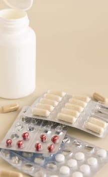 Mix of pills and capsules in a aluminum and plastic blisters with some missing pills already used on light beige close up, copy space. Preventive medicine and healthcare, dietary supplements