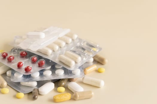 Mix of pills and capsules in a aluminum and plastic blisters with some missing pills already used on light beige close up. Preventive medicine and healthcare, taking dietary supplements and vitamins