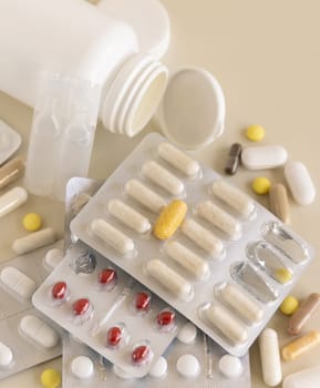 Mix of pills and capsules in a aluminum and plastic blisters with some missing pills already used on light beige close up. Preventive medicine and healthcare, taking dietary supplements and vitamins