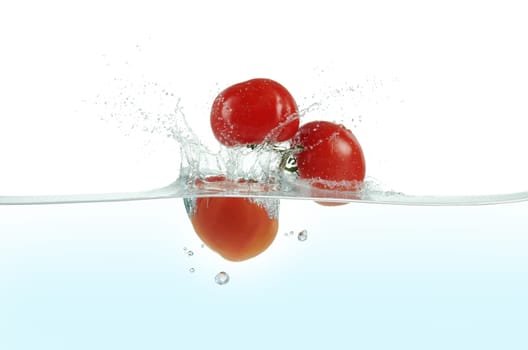 Three tomatoes splashing in water. Side view on white background.