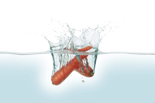 Two carrots splashing in water. Side view on white background.