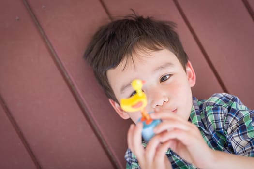 Portrait of Mixed Race Chinese and Caucasian Young Boy Laying On His Porch Playing With Toy