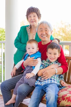 Senior Adult Chinese Couple Sitting With Their Mixed Race Grandchildren