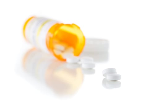 Non-Proprietary Medicine Prescription Bottle and Spilled Pills Isolated on a White Background.