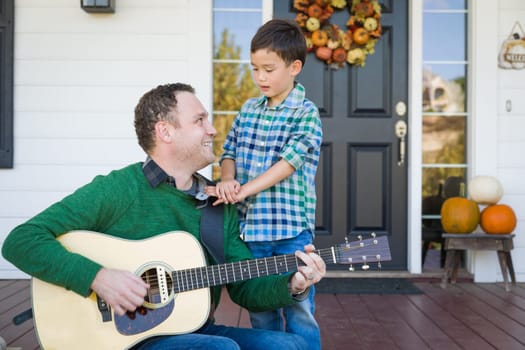 Young Mixed Race Chinese and Caucasian Son Singing Songs and Playing Guitar with Father