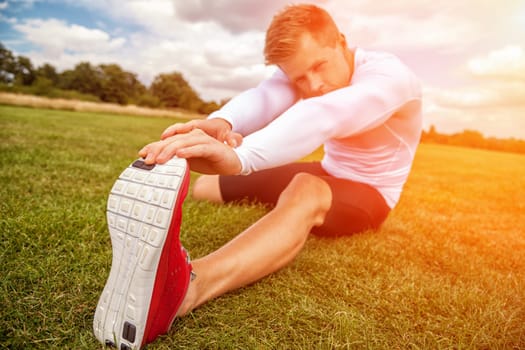 Stretching out muscles in the park on a sunny day, with focus on hand