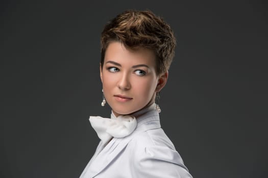 portrait of an elegant young doctor in a white coat and a white scarf, tied in a bow against a dark background