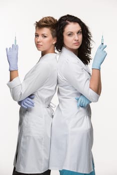 Portrait of two women surgeons holding in their hands syringes isolated on white background