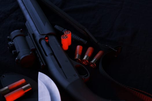 Weapon on black cloth: knife, rifle, shells,top view. Top view of knife, rifle shells