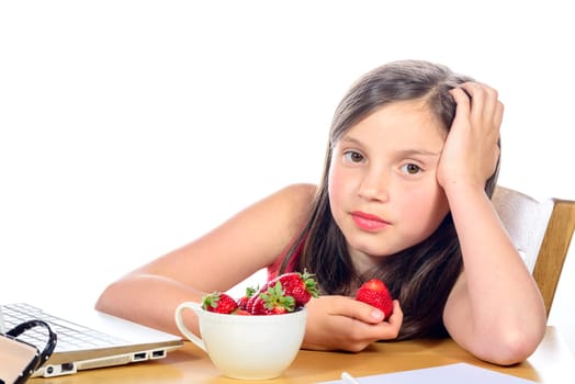 a little girl eating a strawberry on her desk
