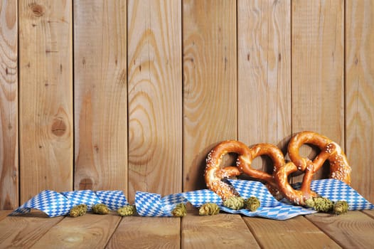 Two original Bavarian lye pretzels with hops with Bavarian diamond pattern on old wooden boards