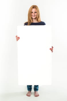 Young blond woman holding a blank banner, standing in jeans and barefoot - isolated over a white background