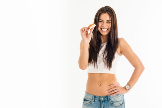 Young attractive asian-caucasian woman holding sushi with her fingers, sexy fashion and pierced bellybutton, isolated on white background
