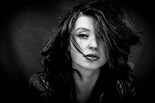 Stylized bw portrait of a brunette pierced young adult woman wearing a leather jacket
