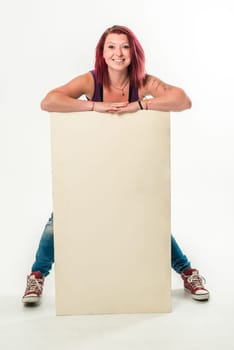 Young red-haired woman holding a blank banner, standing in jeans and red chucks - isolated over a white background