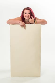 Young red-haired woman holding a blank banner, thumb turned up, top, standing  isolated over a white background