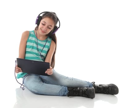Beautiful pre-teen girl using a tablet computer and headphones.
