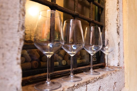 Four empy wine glasses over a windows out of a venetian winery