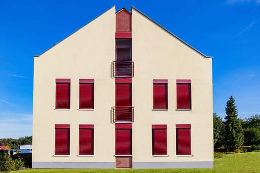 Modern House Facade with red windows and balcony.