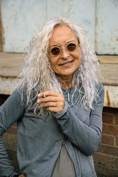 Beautiful woman with long bright curly hair is smoking a cigarette.