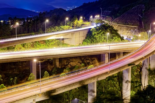 moving car on highway bridge with light through city at night