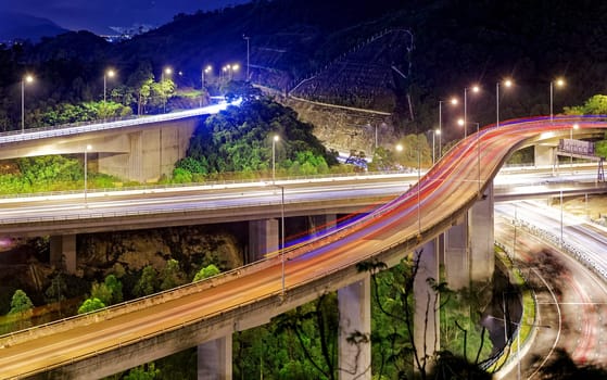 moving car on highway bridge with light through city at night