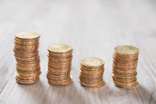 Coins stack in row on wooden background, financial concept. Focus on foreground with blur background.