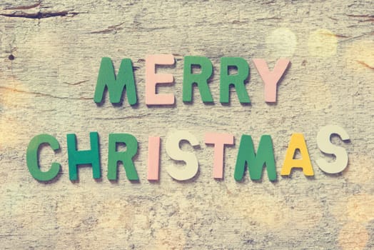 The colorful words "MERRY CHRISTMAS"" made with wooden letters on old wooden board."