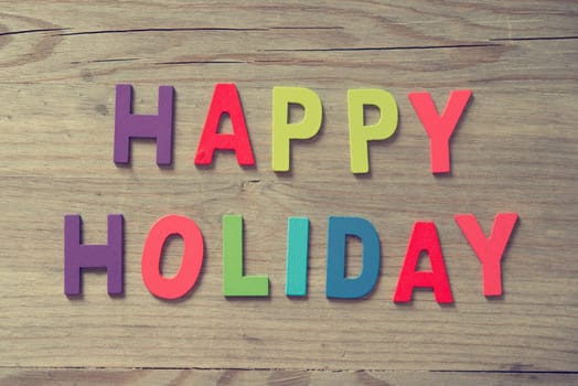 The words "HAPPY HOLIDAYS"" on wooden plank."