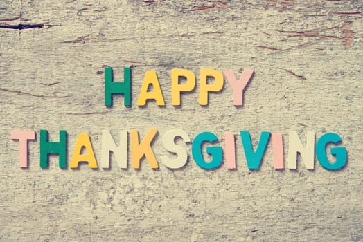 The colorful words "HAPPY THANKSGIVING"" made with wooden letters on old wooden plank."