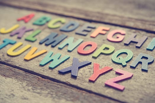 Colorful wooden English alphabet set on grunge wooden background, focus on alphabet X.