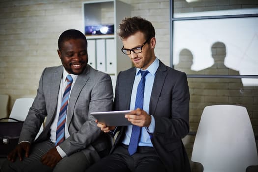 Two male colleagues looking through data in office