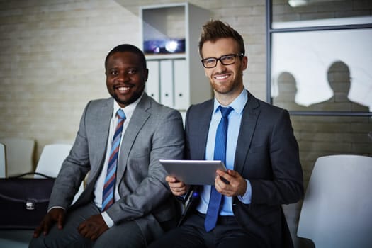 Two male colleagues looking at camera during work in office