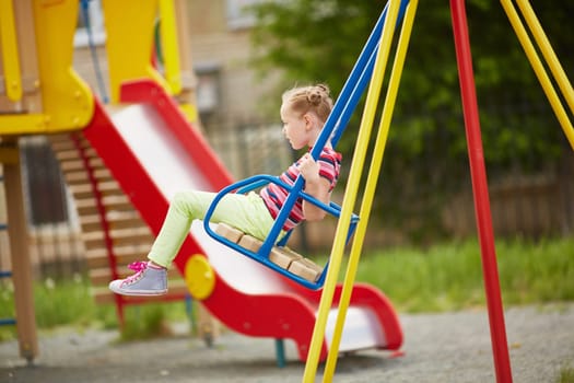Cute girl swinging on playground area