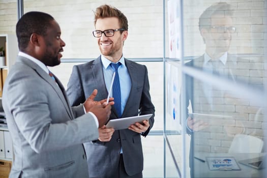 Two confident colleagues sharing ideas at meeting in office