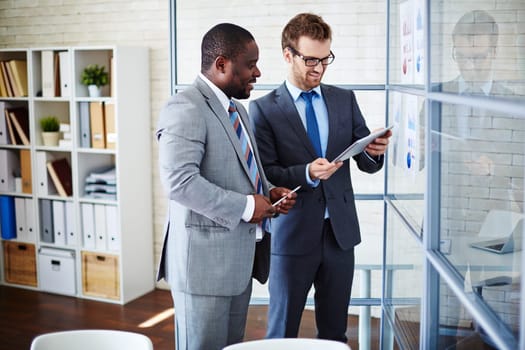 Two businessmen looking at data in touchpad at meeting