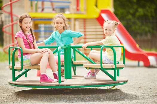 Friendly girls riding on carousel at leisure