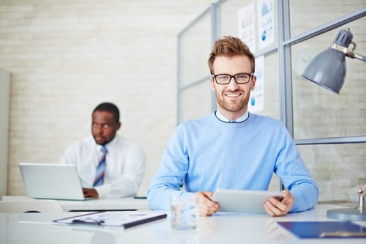 Young man with touchpad looking at camera at workplace
