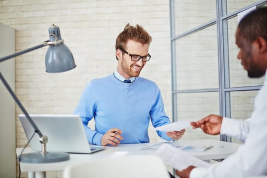 Young manager reading resume of man hiring for job