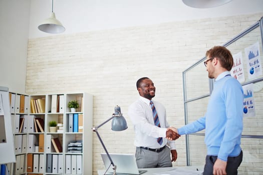 Young employer congratulating newly hired man