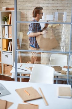 Young architect with blueprint reading papers on wall