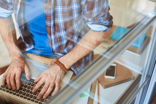 Young businessman hands pushing laptop keys