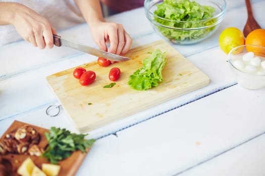 Hands of female cutting ingredients for Greek salad