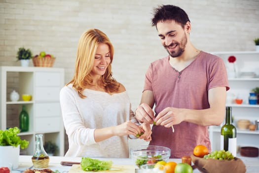 Amorous young couple cooking salad together