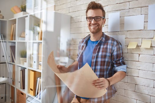 Happy businessman with document looking at camera by the wall